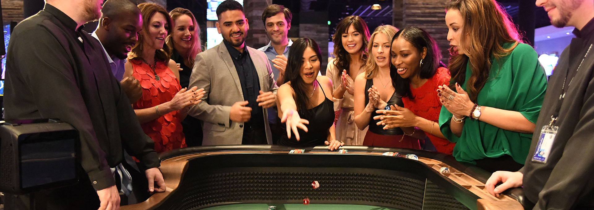 Woman throwing the dice at the craps table, surrounded by guests